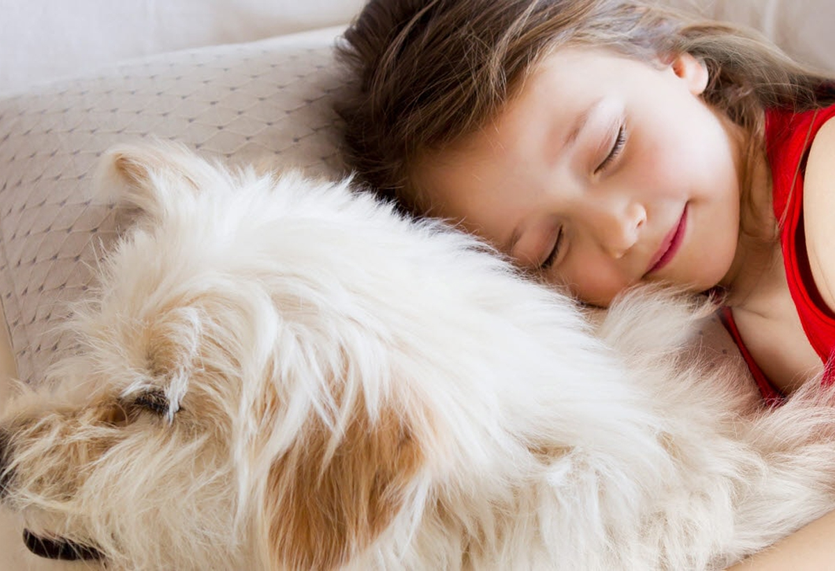 Ένα παιδί κοιμάται αγκαλιά με τον σκύλο του.